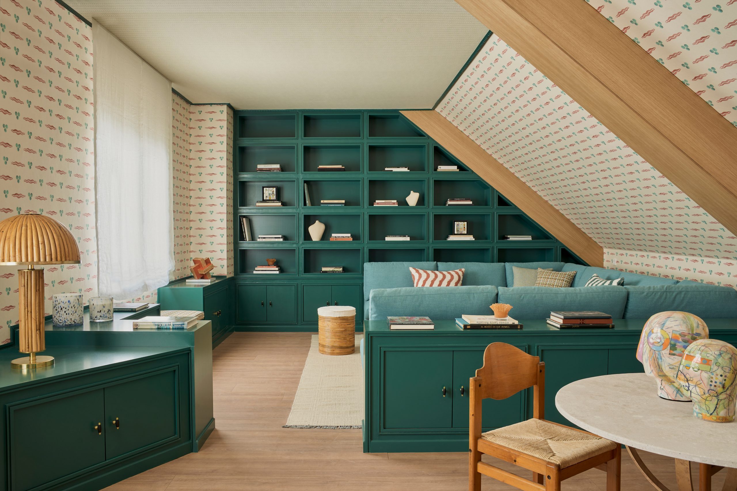 Buhardilla con librería verde, sofá de terciopelo y papel pintado