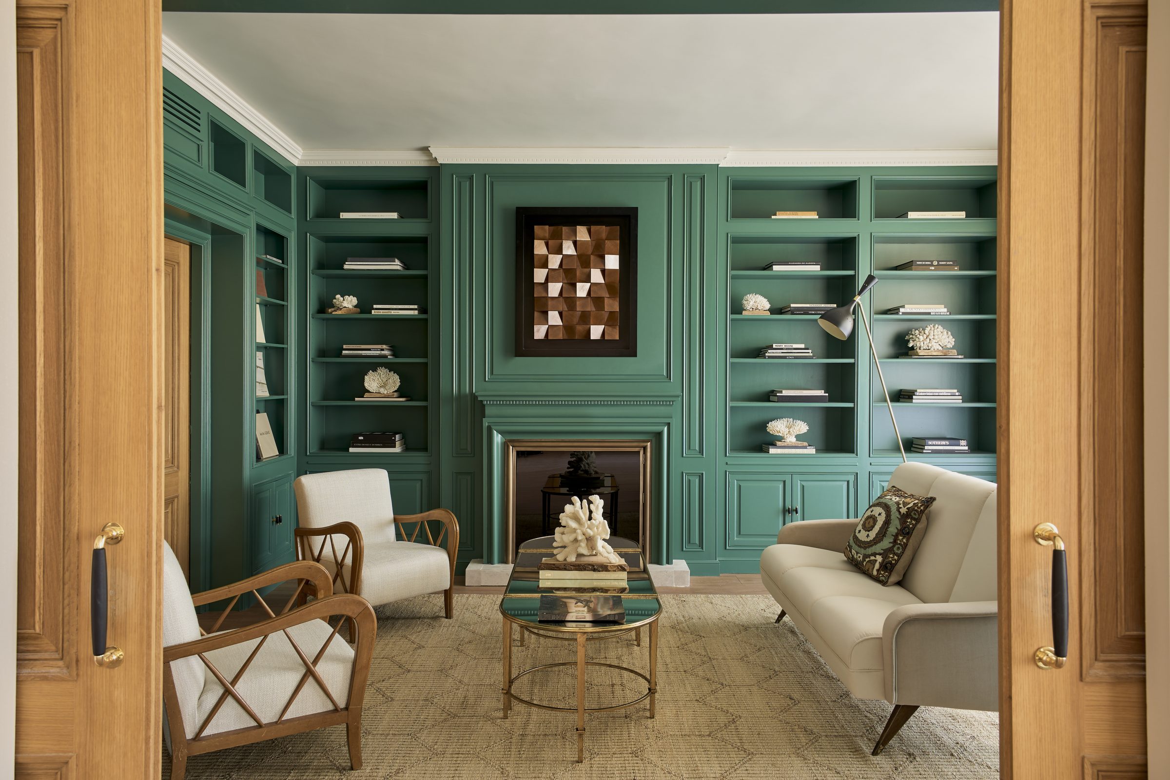 Salón con librerías lacadas en verde y chimenea