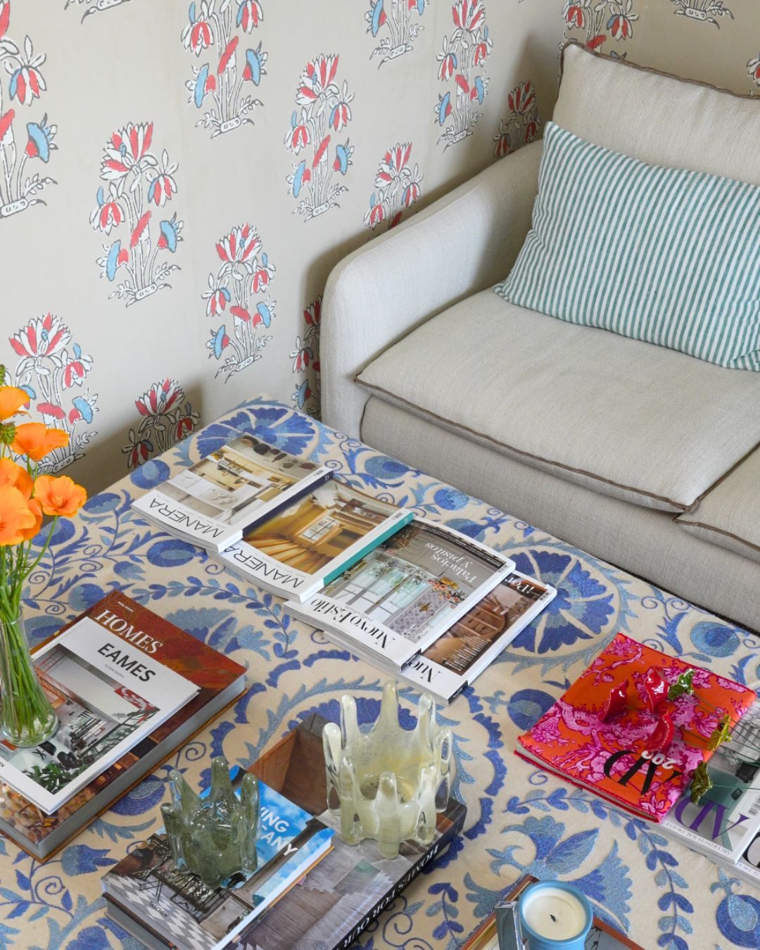 Sofá y mesa con revistas de decoración sobre un mantel estampado