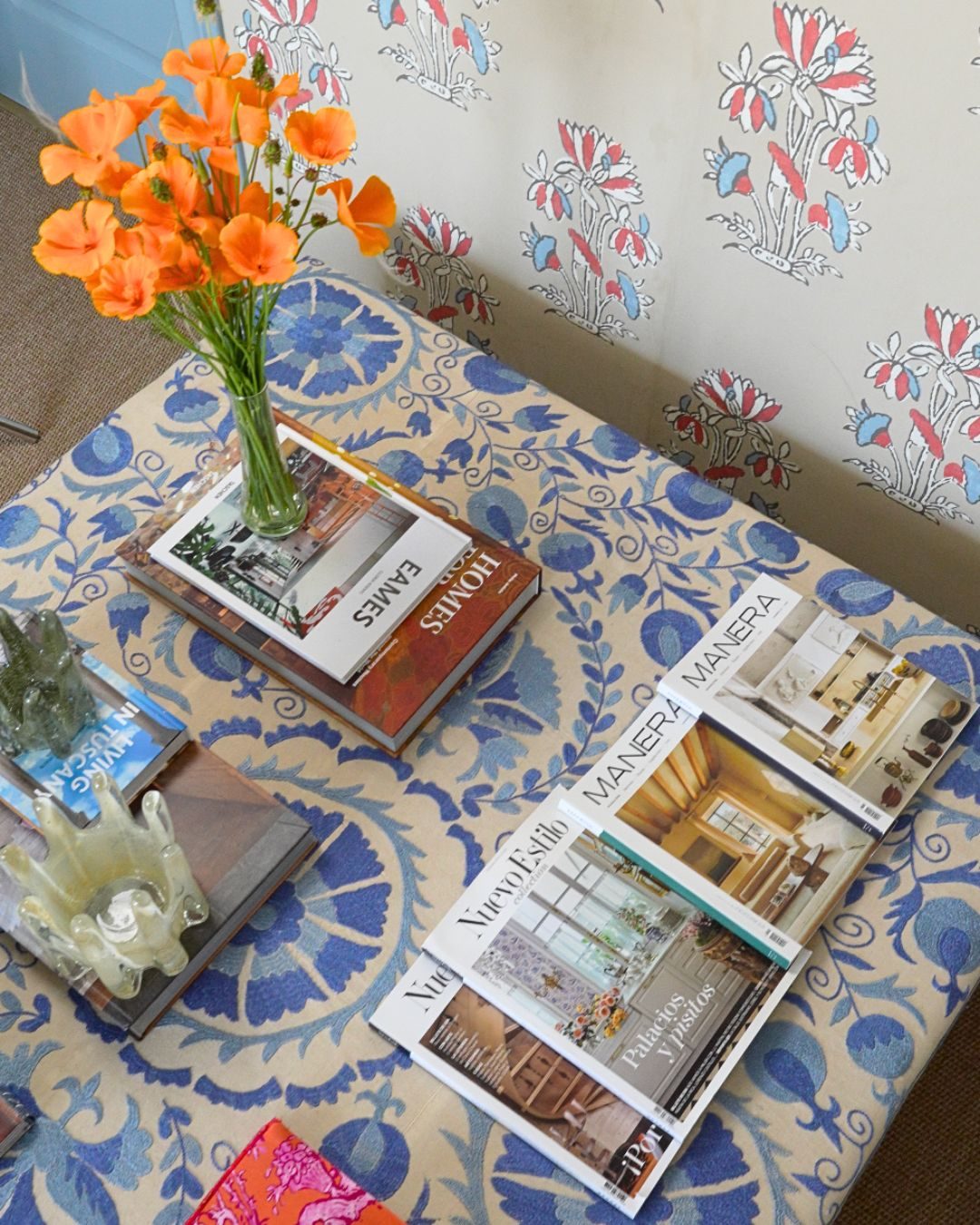 Revistas de interiorismo y flores naranjas sobre un mantel azul