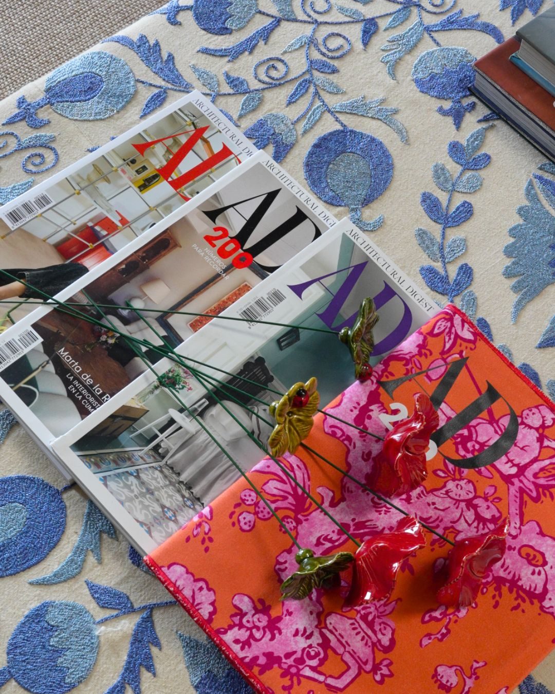 Revistas de decoración y flores fucsias sobre un mantel estampado
