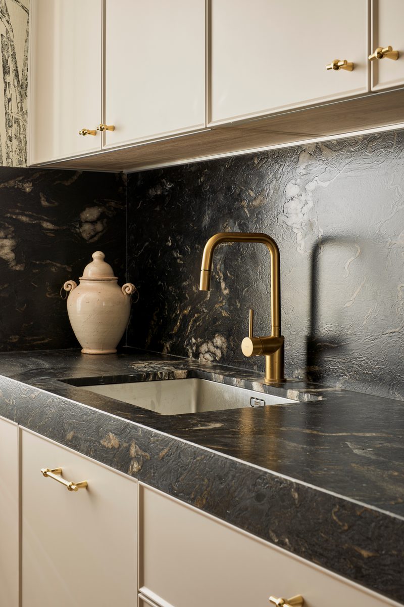 Detalle de cocina con encimera de mármol negro y grifería dorada